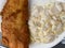 Closeup of isolated breaded fried fish with greasy mayonnaise potato salad on white paper plate in dutch fast food restaurant