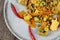 Closeup of isolated china plate with spicy fresh thai fried rice food, carrots, peas, shrimps, chicken, Chillies, maize, eggs