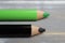 Closeup of isolated colorful black and green crayons on wood background - kiwi coalition concept