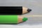 Closeup of isolated colorful black and green crayons on wood background - kiwi coalition concept