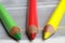 Closeup of isolated colorful yellow, red, green crayons on wood background - traffic light coalition concept