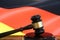 Closeup of isolated judge wood gavel with blurred german flag background focus on hammer head