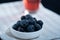 Closeup of a jar of blueberries ona kitchen towel. A glass of blueberry juice in the background