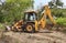 Closeup of JCB cleaning land for construction of building at forest or countryside