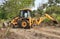 Closeup of JCB cleaning land for construction of building at forest or countryside