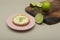 Closeup of a key lime tartlet on a pink plate with key lime fruits on a wooden board