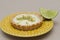 Closeup of a key lime tartlet on a plate with a slice of key lime fruit on the side