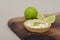Closeup of a key lime tartlet on a wooden board with key lime fruits