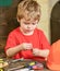 Closeup kid playing with metal bolts. Little laborer in workshop. Cute boy in red T-shirt behind the table