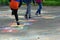 Closeup of kids feet jumping and playing hopscotch at school