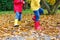 Closeup of kids legs in rubber boots dancing and walking through fall leaves