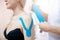 Closeup kinesiology taping to patient shoulder athlete woman