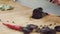 Closeup of knife cuts sausage. Scene. Close-up of cutting dark salami on wooden cutting board. Salt on background of