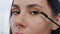 Closeup lady applying eyelashes mascara makeup indoors. Pov serious woman visage