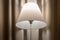 Closeup of a lamp lights up a modern hotel room, beige curtain with folds