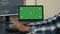 Closeup of laptop with green screen chroma key mockup and african american hands writing code