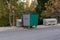 Closeup of large trash bin along the street with trees background