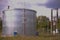 Closeup of a large water tank on a grassy landscape against a cloudy sky