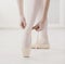 Closeup legs of ballerina puts on pointe ballet shoes