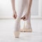 Closeup legs of ballerina puts on pointe ballet shoes