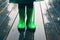 Closeup of legs of kid standing on a porch wearing green wellies and raincoat