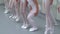 Closeup legs of little ballerinas group standing in row jumping in classical ballet dance studio