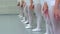 Closeup legs of little ballerinas group in white shoes in row practicing in classical ballet school