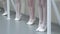 Closeup legs of little ballerinas group in white shoes in row practicing in classical ballet school