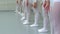 Closeup legs of little ballerinas group in white shoes in row practicing in classical ballet school