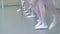 Closeup legs of little ballerinas group in white shoes in row practicing in classical ballet studio