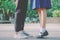 Closeup legs and sneakers of young beautiful couple in school uniform standing on the street in park summer evening,