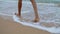 Closeup legs walking ocean beach. Slim woman feet going splashing waves alone.