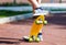 Closeup of the legs and yellow skateboard. Boy rising a board on two wheels, focus on skate.