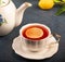 Closeup of lemon teapot and tea cup with blue background