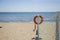 Closeup of lifeguard orange lifebuoy on the beach with sea in th