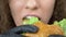 Closeup of the lips. woman eats a juicy hamburger, hands in black rubber gloves