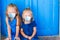 Closeup of Little adorable girls sitting near old blue door in Greek village, Emporio, Santorini