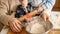 Closeup of little baby boy kneading dough and flour in bowl for making bread with mother. Concept of little chef