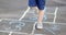 Closeup of little boy`s legs and hopscotch drawn on asphalt