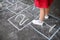 Closeup of little girl`s legs and hopscotch drawn on asphalt. Child playing hopscotch game on playground outdoors on a sunny day