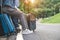 Closeup lower body of Asian couple relaxing on SUV car trunk with yellow trolly luggage along road trip with mountain hill