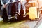 Closeup lower body of group of friends relaxing on SUV car trunk with trolly luggage along road trip with autumn mountain hill