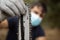 Closeup of a lumberjack in a medical mask with a chainsaw in a forest