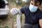 Closeup of a lumberjack in a medical mask with a chainsaw in a forest