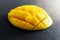 Closeup of lush ripe mango cut in half and diced on dark slate cutting board