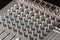 Closeup macro audio mixing console knobs and sliders.