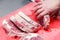 Closeup macro cook`s hand cut ribeye marbled beef steak with knife on red plastic cutting board on metal table in restaurant