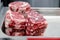 Closeup macro pieces ribeye marbled beef steak on red plastic cutting board on metal table in restaurant kitchen. Concept packing