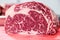 Closeup macro pieces ribeye marbled beef steak on red plastic cutting board on metal table in restaurant kitchen. Concept packing