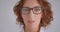 Closeup macro portrait of adult redhead caucasian businesswoman in glasses looking at camera indoors in the white